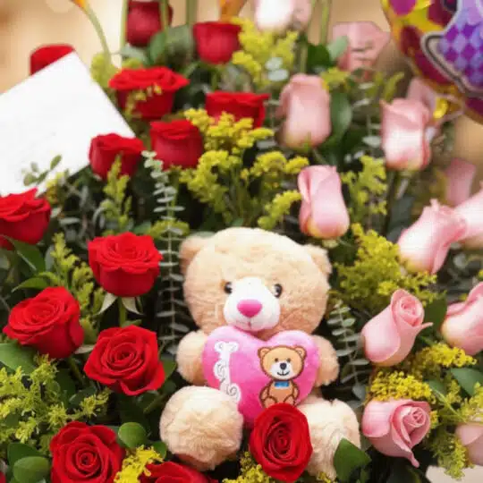 Primer plano extremo de Arreglo Floral Exótico Especial con rosas rojas y rosadas, follaje verde, gotas de rocío y un osito d