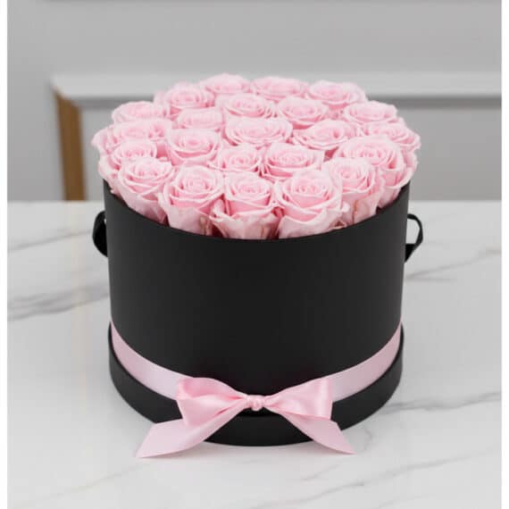 Arreglo floral Francesca con 21 rosas rosadas preservadas en una caja cilíndrica negra con lazo rosa, ideal para regalo.