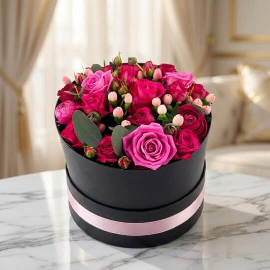 Arreglo floral LILIAN en caja negra con cinta rosa, lleno de rosas lila y rojas, ideal para regalar.