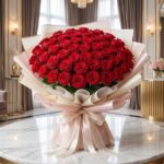 Imponente Bouquet PAOLA con 72 rosas rojas frescas y abiertas, envuelto en elegante empaque coreano, sobre mesa de mármol en