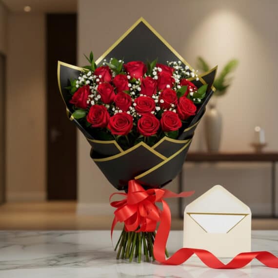 Bouquet de rosas rojas frescas y gypsophila envuelto en papel negro y dorado, atado con una cinta de satén rojo, sobre una su