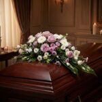 Cubre caja fúnebre "Jardín de Ines" con rosas lilas, margaritas blancas y flores moradas sobre un ataúd de madera oscura en u