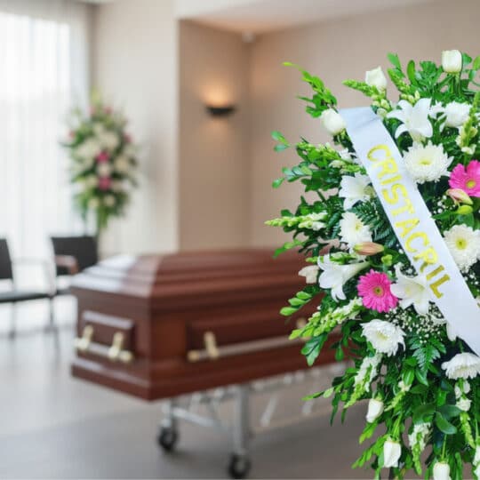 Pedestal fúnebre Sagrado con flores blancas y fucsias, cinta personalizada, en primer plano de una sala de velación moderna c